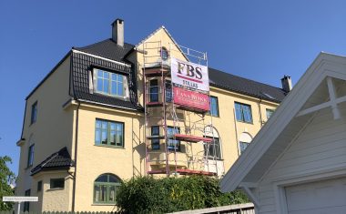 Picture showing an old, large, yellow building with a scaffold tower on the front. Scaffold delivered by FBS. FBS - spesialist på lift og stillas.